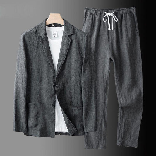 Completo casual uomo in lino grigio, giacca e pantaloni con coulisse, su sfondo grigio. Abbigliamento estivo elegante e confortevole.