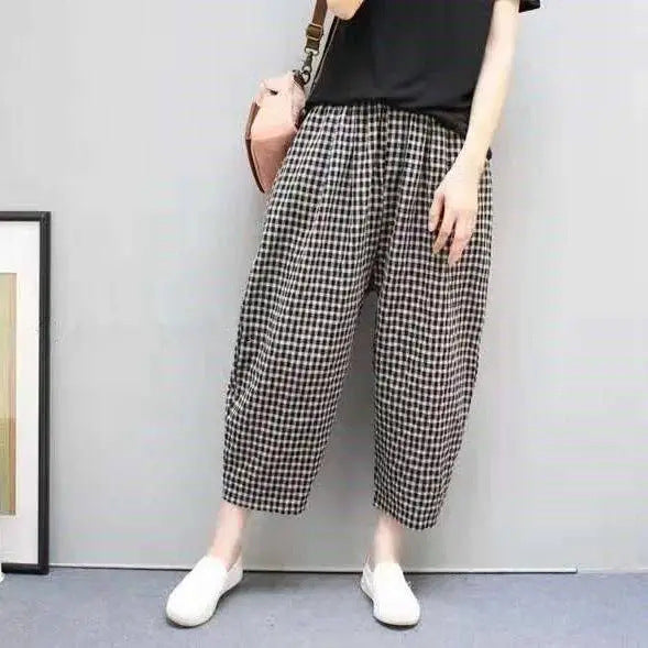 Pantaloni a quadri bianchi e neri, stile casual, indossati con maglietta nera e scarpe bianche, moda donna, outfit estivo, tendenze 2023.