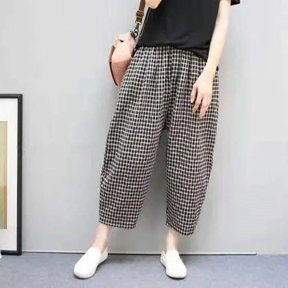 Pantaloni a quadri bianchi e neri, stile casual, indossati con maglietta nera e scarpe bianche, moda donna, outfit estivo, tendenze 2023.