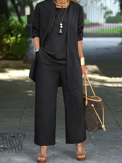 Donna in elegante completo nero, pantaloni larghi e giacca, con borsa di lusso marrone e sandali con zeppa. Moda urbana chic, look sofisticato.