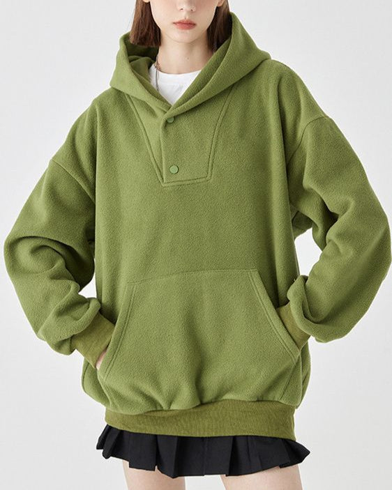 Donna con felpa verde oversize, cappuccio e tasca frontale, indossa una gonna nera. Moda casual autunno, abbigliamento comodo e trendy.