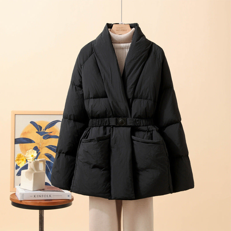 Giacca imbottita nera elegante su manichino, con cintura in vita, sfondo beige. Moda invernale, cappotto caldo, stile casual chic.