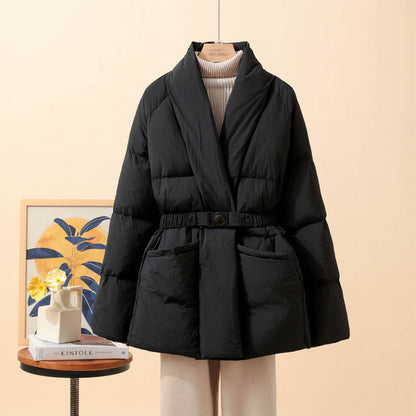 Giacca imbottita nera elegante su manichino, con cintura in vita, sfondo beige. Moda invernale, cappotto caldo, stile casual chic.