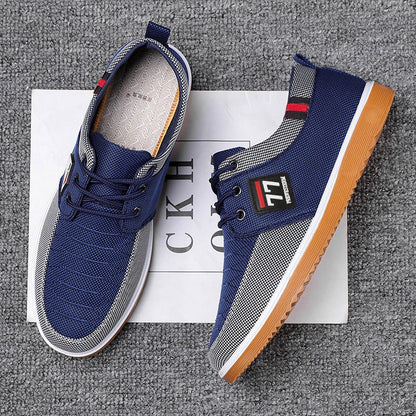 Scarpe da ginnastica blu da uomo su sfondo grigio, con suola in gomma marrone e dettagli rossi e neri. Design moderno e casual.