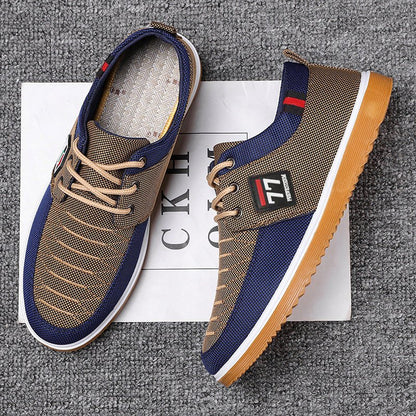 Scarpe casual da uomo blu e beige su sfondo grigio, con suola in gomma gialla e dettagli a righe, ideali per moda urbana e comfort quotidiano.