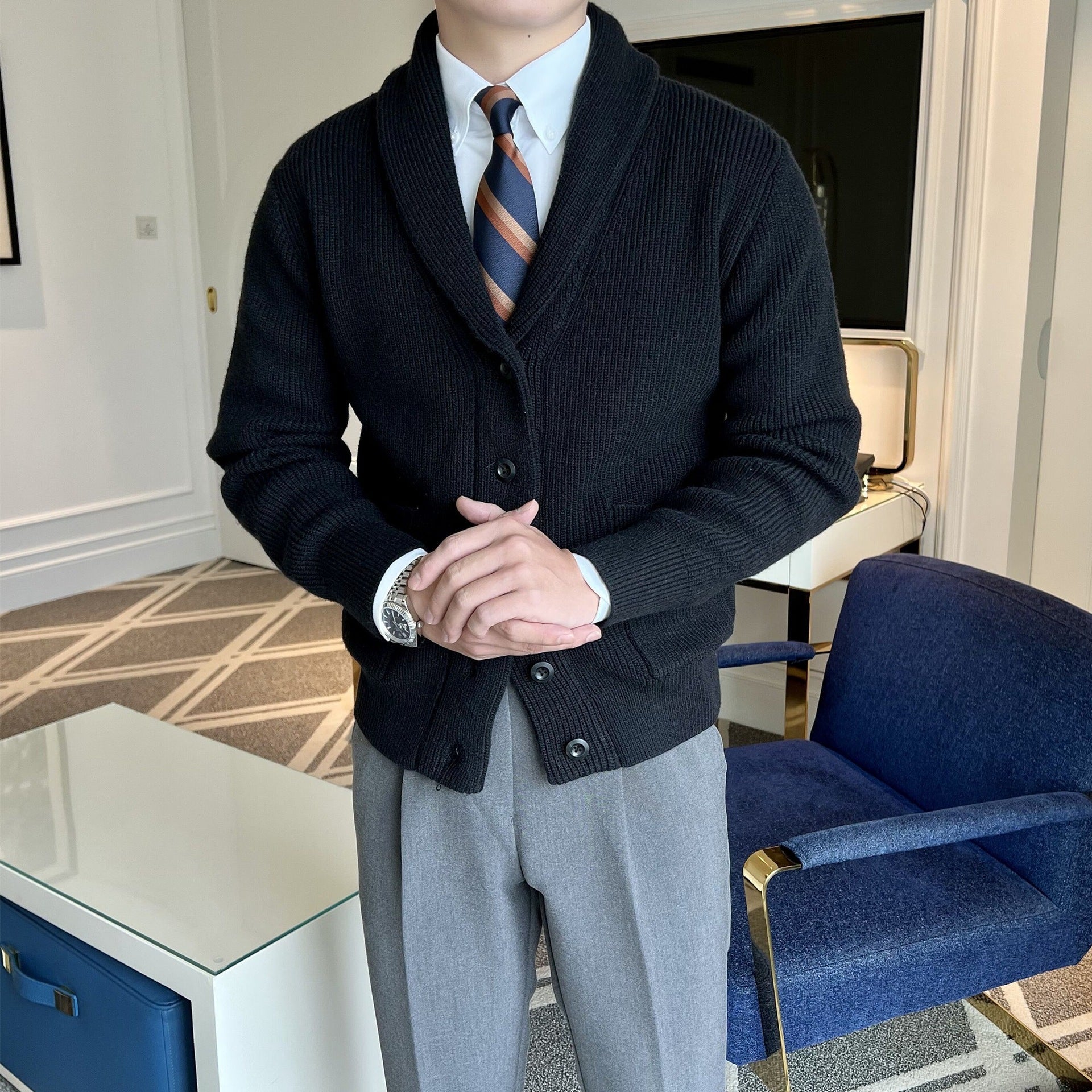 Uomo in cardigan nero e cravatta a righe, in ufficio moderno. Moda maschile elegante, abbigliamento formale, stile business casual.