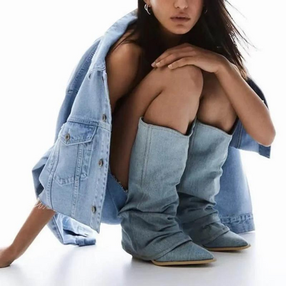 Donna con giacca e stivali di jeans, seduta in posa moderna. Moda denim, stile casual chic, tendenze abbigliamento autunno-inverno.