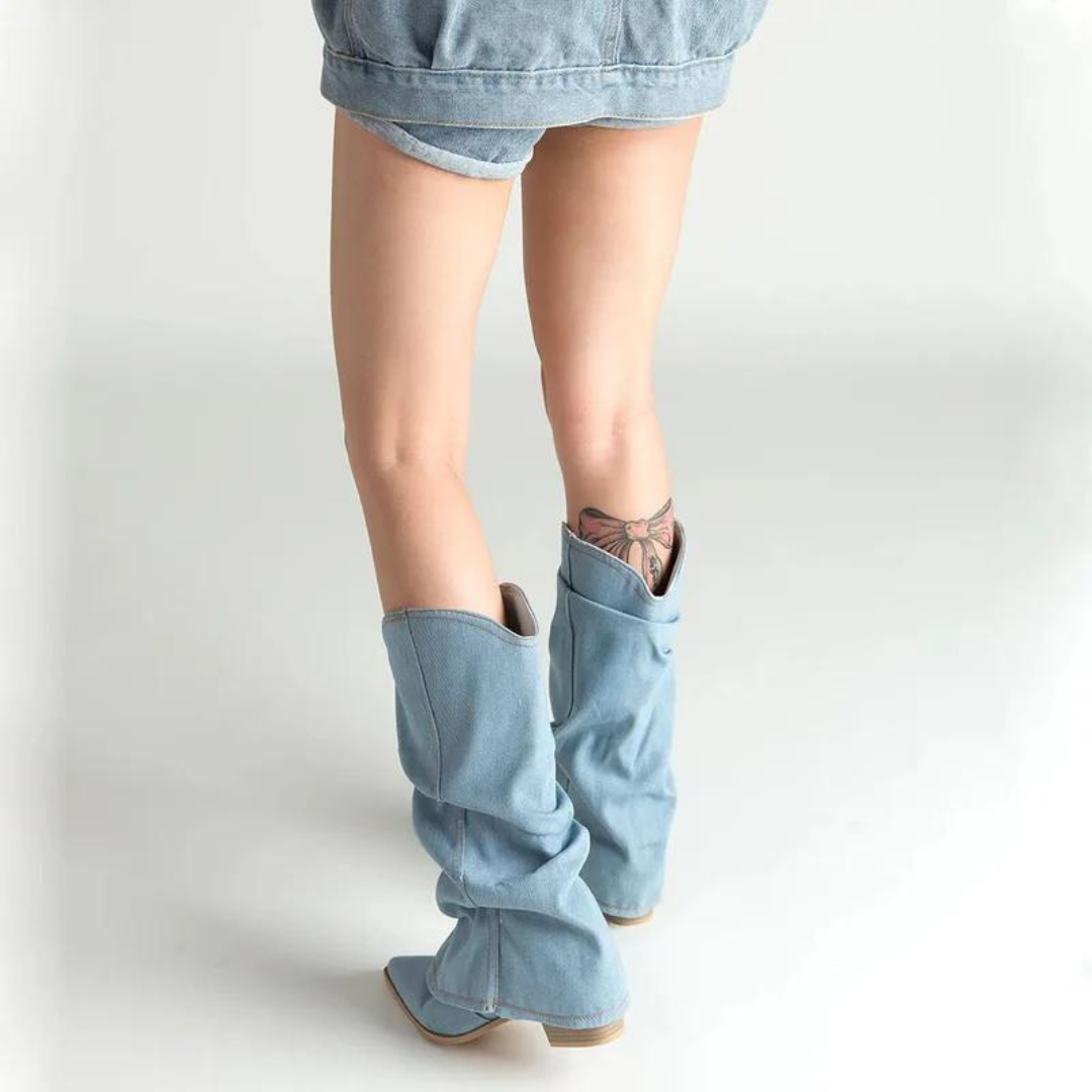 Stivali alti in denim chiaro su gambe femminili, abbinati a shorts di jeans. Moda casual, stile urbano, tendenze calzature 2023.