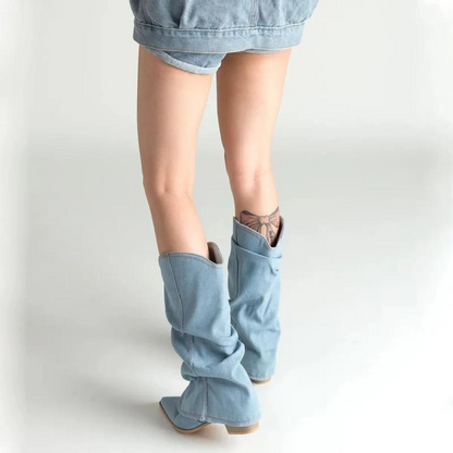 Stivali alti in denim chiaro su gambe femminili, abbinati a shorts di jeans. Moda casual, stile urbano, tendenze calzature 2023.