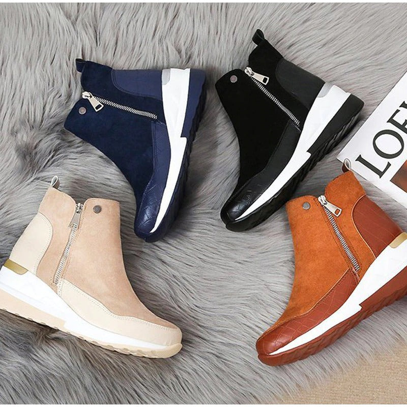 Quattro stivaletti da donna su tappeto grigio: blu, nero, beige e marrone, con zip laterale e suola bianca. Scarpe moda autunno inverno.