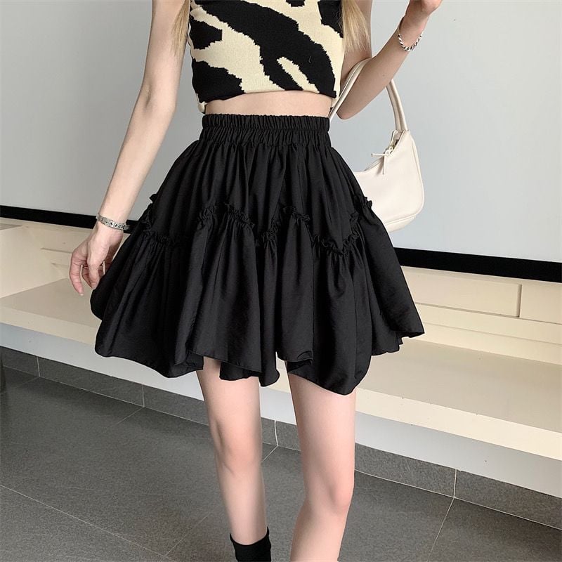 Donna con top a fantasia zebrata e gonna nera a balze, borsa bianca a spalla. Moda estiva, abbigliamento casual chic.