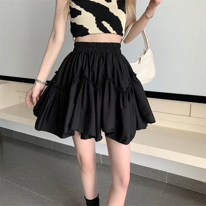 Donna con top a fantasia zebrata e gonna nera a balze, borsa bianca a spalla. Moda estiva, abbigliamento casual chic.