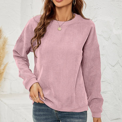 Donna con maglione rosa in velluto a coste, jeans blu, sfondo bianco. Moda casual autunnale, abbigliamento femminile trendy, stile confortevole.