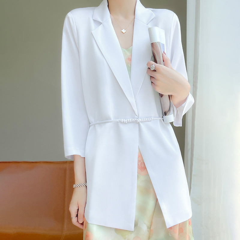 Donna in abito elegante bianco, blazer lungo, con accessori raffinati. Moda femminile, stile sofisticato, abbigliamento formale.