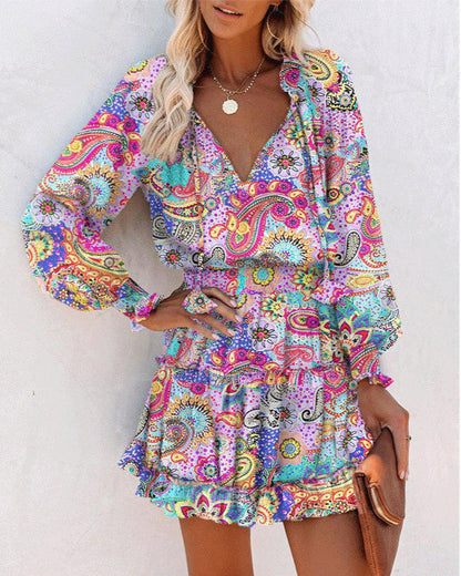 Donna con abito estivo colorato a fantasia paisley, maniche lunghe, scollo a V, accessori oro, borsa marrone. Moda estiva, abbigliamento femminile.