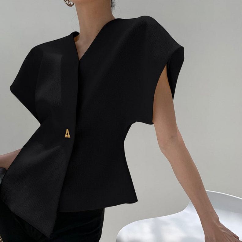 Donna con elegante top nero asimmetrico, senza maniche, con dettaglio dorato. Moda minimalista, abbigliamento femminile moderno e sofisticato.