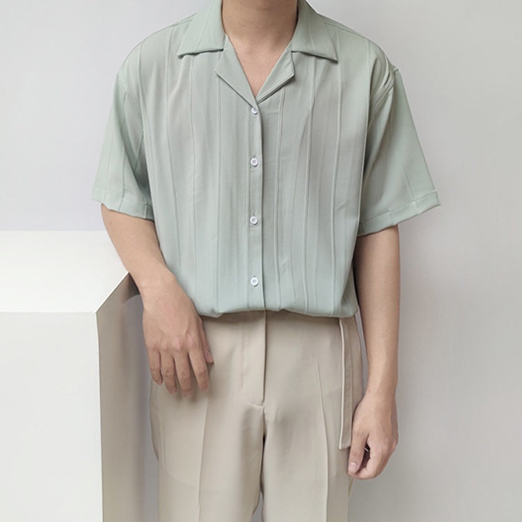 Camicia verde chiaro a righe verticali, maniche corte, indossata da uomo con pantaloni beige. Moda estiva elegante e casual.