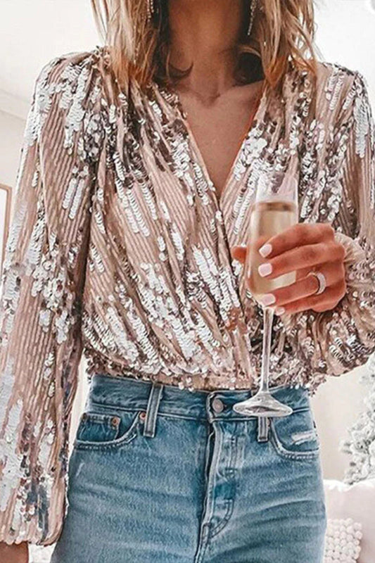 Donna in top di paillettes argento e jeans, tiene un bicchiere di champagne. Moda elegante, abbigliamento da festa, stile glamour.