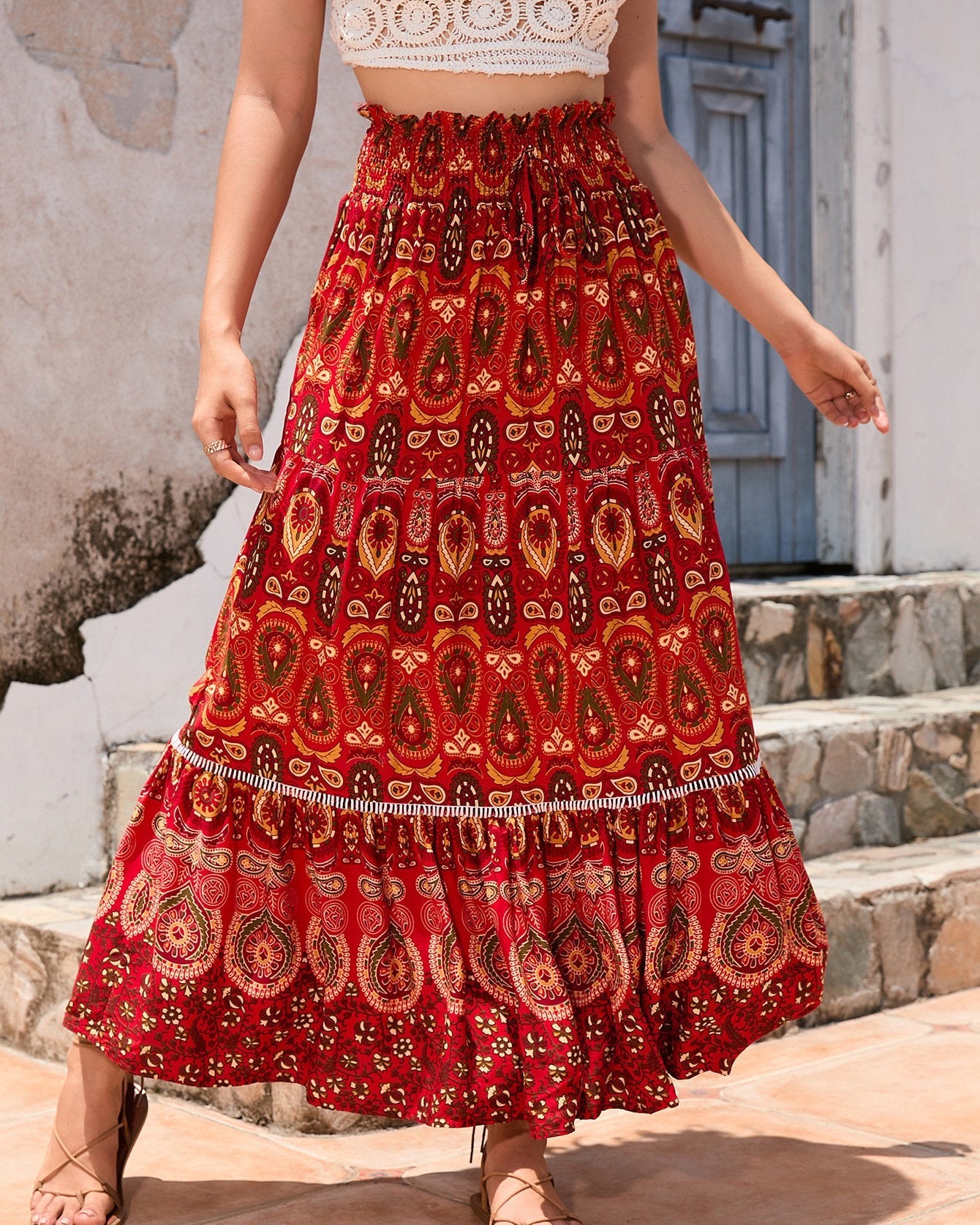 Gonna lunga boho rossa con motivi paisley, indossata da una donna su sfondo esterno. Moda estiva, abbigliamento casual, stile bohemien.