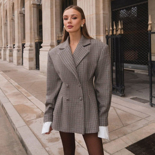 Donna elegante in blazer a quadri oversize, posa davanti a un edificio storico. Moda autunnale, stile urbano chic, tendenze abbigliamento 2023.