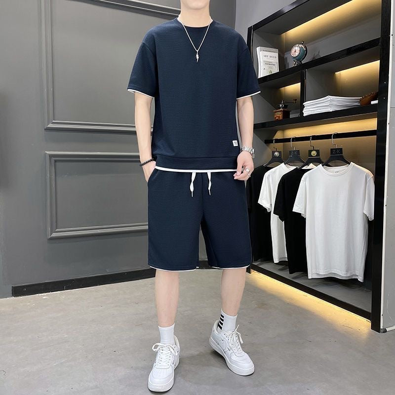 Uomo in abbigliamento casual estivo, indossa t-shirt e pantaloncini blu scuro, scarpe da ginnastica bianche, in negozio di moda maschile.