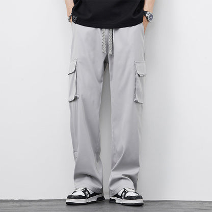 Pantaloni cargo grigi da uomo con tasche laterali, cordoncino in vita, abbinati a scarpe sportive bianche e nere. Moda casual maschile.