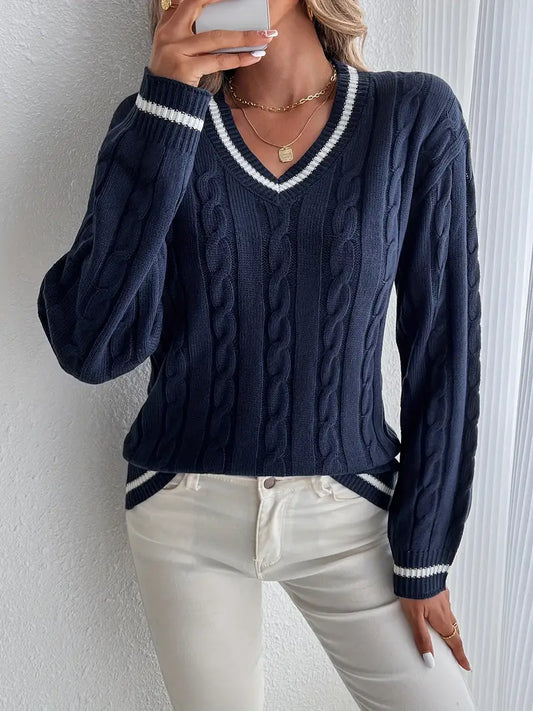 Maglione blu a trecce con scollo a V e dettagli bianchi, indossato con jeans bianchi. Stile casual elegante, moda autunnale donna.