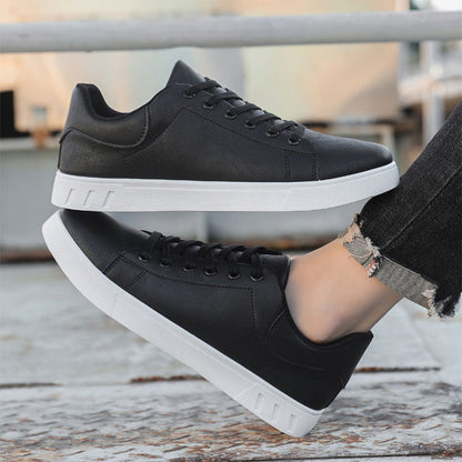 Scarpe da ginnastica nere unisex con suola bianca, indossate su pavimento esterno. Design moderno, casual, perfette per moda urbana e comfort quotidiano.