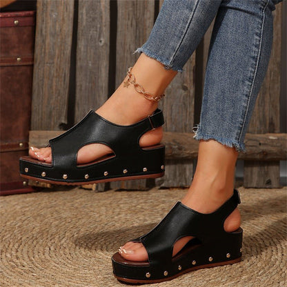 Sandali neri con zeppa e borchie, indossati con jeans strappati. Scarpe estive alla moda, perfette per un look casual e trendy.