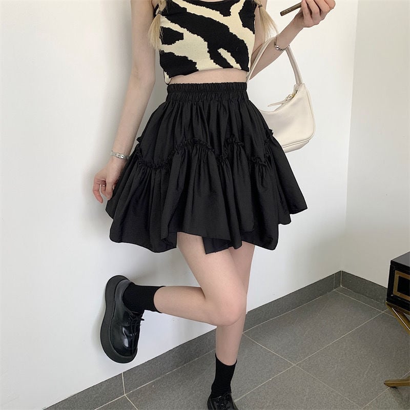 Donna con top zebrato e gonna nera a balze, borsa bianca e scarpe nere lucide. Moda femminile, outfit casual chic, tendenze abbigliamento 2023.