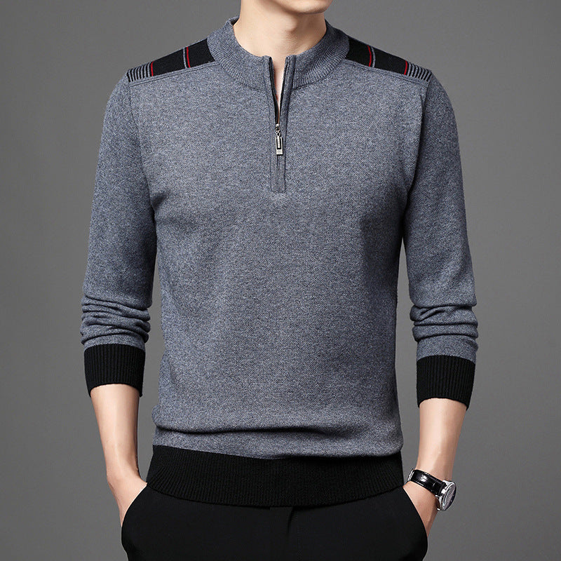 Maglione grigio da uomo con zip, dettagli neri sulle spalle, polsini e orlo a coste, indossato con pantaloni neri. Elegante e moderno.