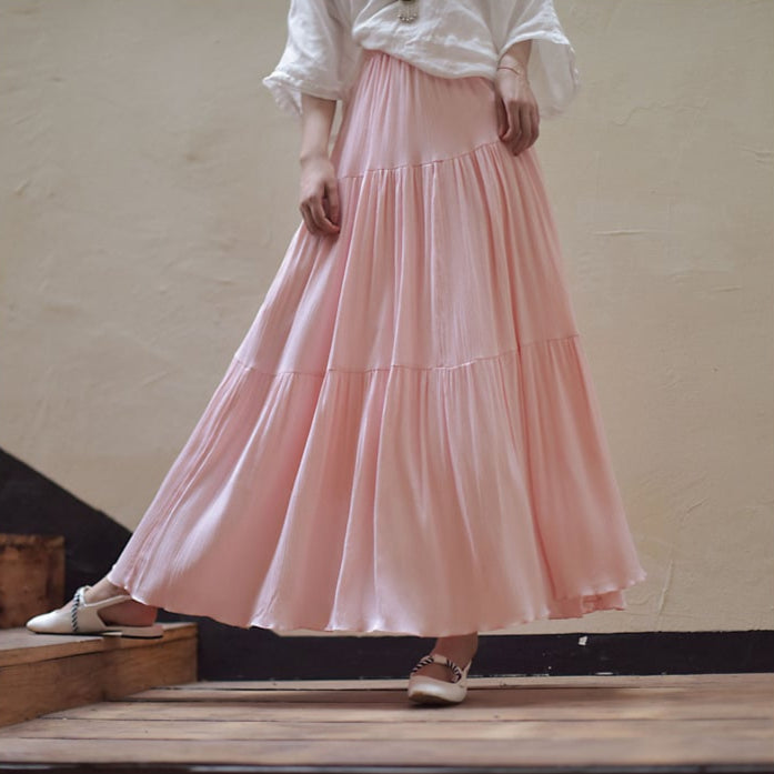 Gonna lunga rosa in tessuto leggero, indossata con camicia bianca e scarpe basse. Moda femminile elegante, abbigliamento estivo casual.