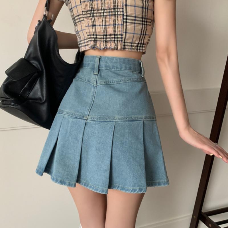 Donna con gonna di jeans a pieghe e top a quadri, borsa nera a spalla. Moda casual estiva, abbigliamento femminile trendy.