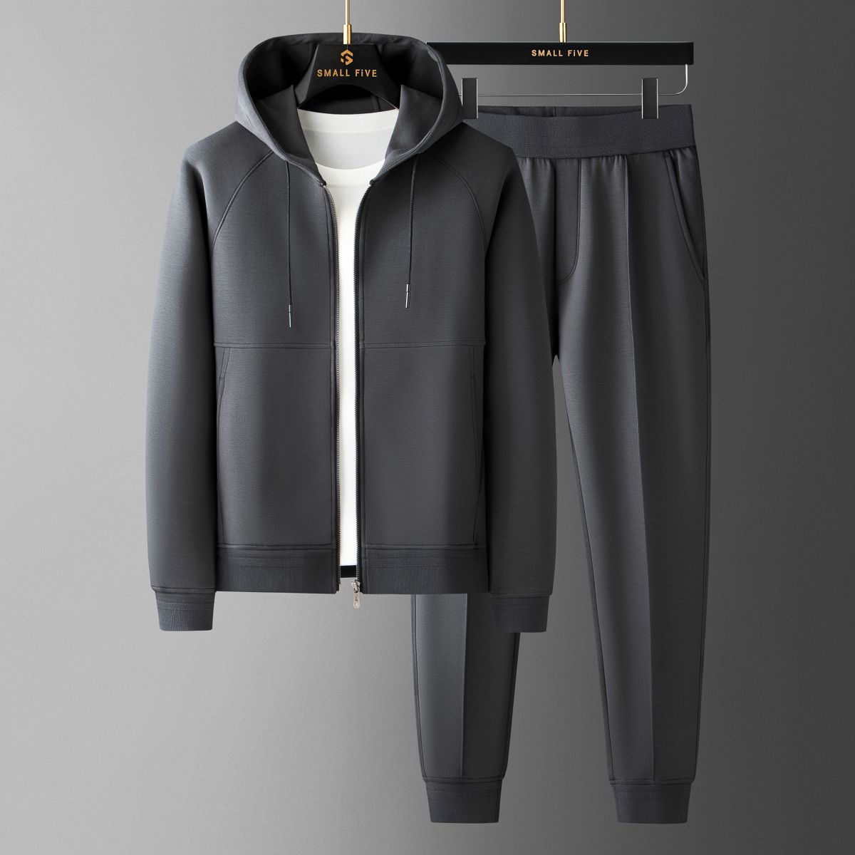 Tuta sportiva grigia con felpa con cappuccio e pantaloni, appesa su grucce. Abbigliamento casual uomo, moda comoda, stile moderno.