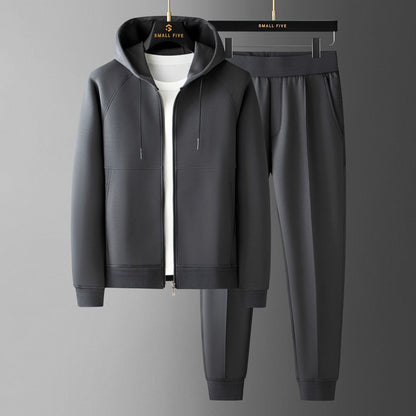 Tuta sportiva grigia con felpa con cappuccio e pantaloni, appesa su grucce. Abbigliamento casual uomo, moda comoda, stile moderno.
