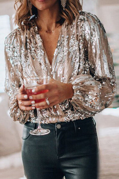 Donna con camicia di paillettes dorate, pantaloni neri, tiene un bicchiere di cocktail rosso. Moda elegante, outfit da festa, stile glamour.