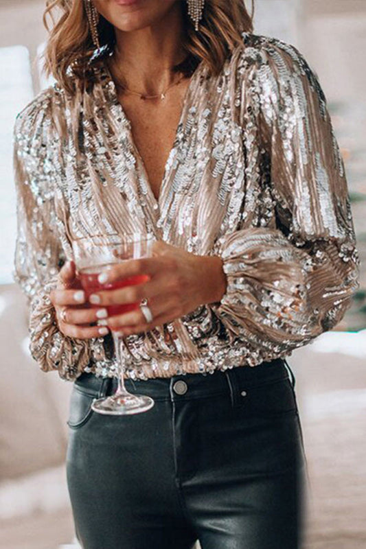 Donna con camicia di paillettes dorate, pantaloni neri, tiene un bicchiere di cocktail rosso. Moda elegante, outfit da festa, stile glamour.