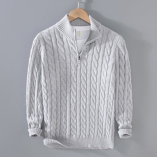 Maglione grigio chiaro a trecce con zip, collo alto, appeso su gruccia. Design elegante e caldo, ideale per moda autunno-inverno.