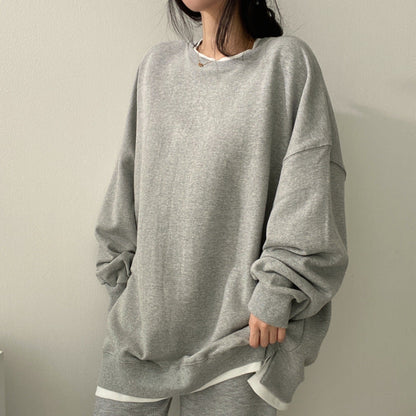 Donna con felpa oversize grigia, stile casual, moda autunnale. Abbigliamento comodo, tendenze streetwear, look minimalista, outfit quotidiano.