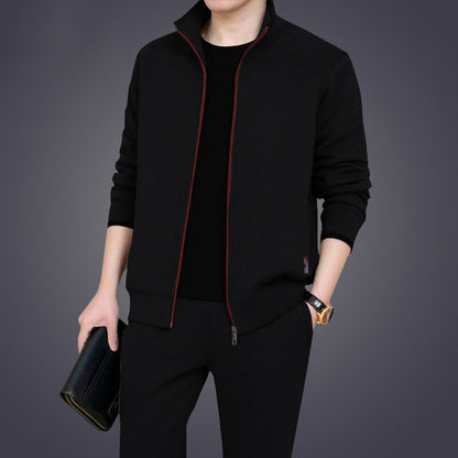 Giacca nera elegante con cerniera rossa, indossata da uomo, abbinata a pantaloni neri. Look moderno e sofisticato, moda maschile autunnale.