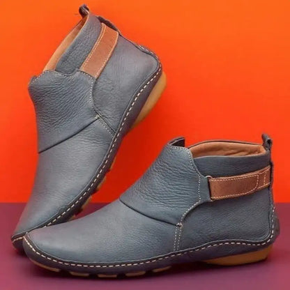 Stivaletti in pelle blu con suola in gomma beige, design moderno e cuciture a vista, sfondo arancione e viola. Scarpe eleganti e casual.