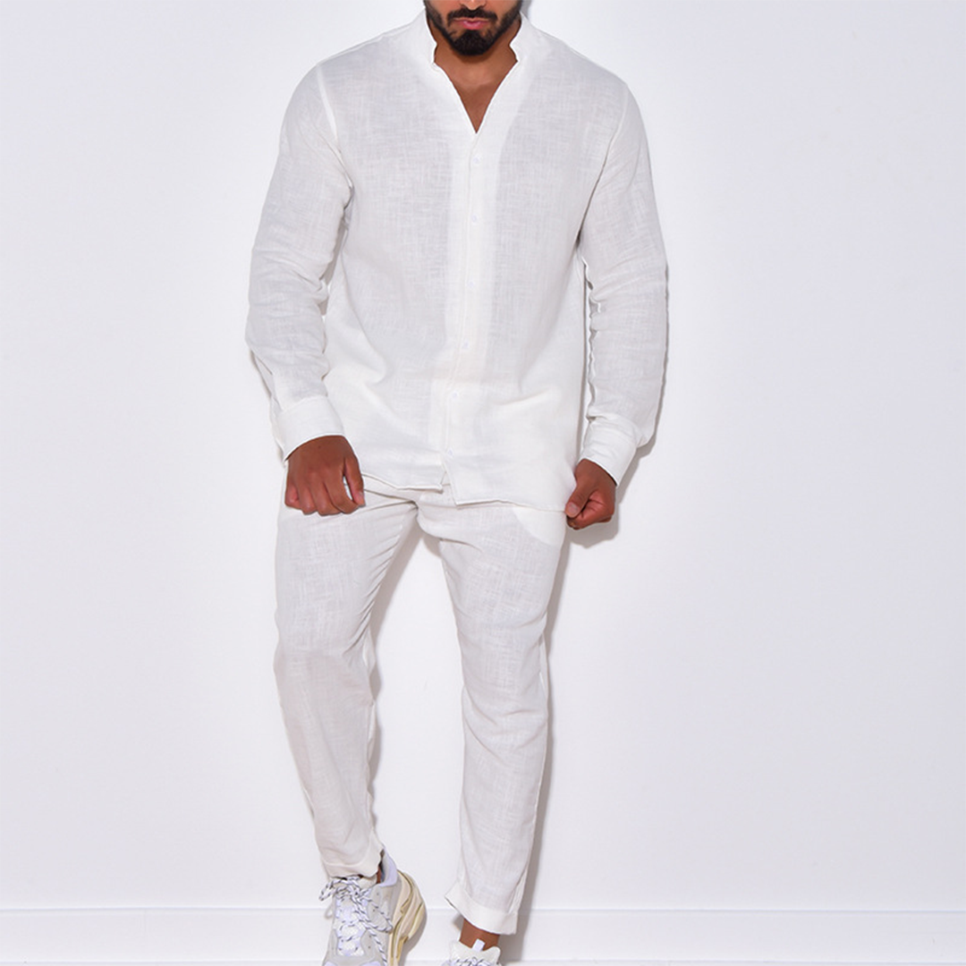 Uomo in abito bianco di lino, camicia e pantaloni, posa contro sfondo bianco. Moda estiva maschile, stile elegante e casual.