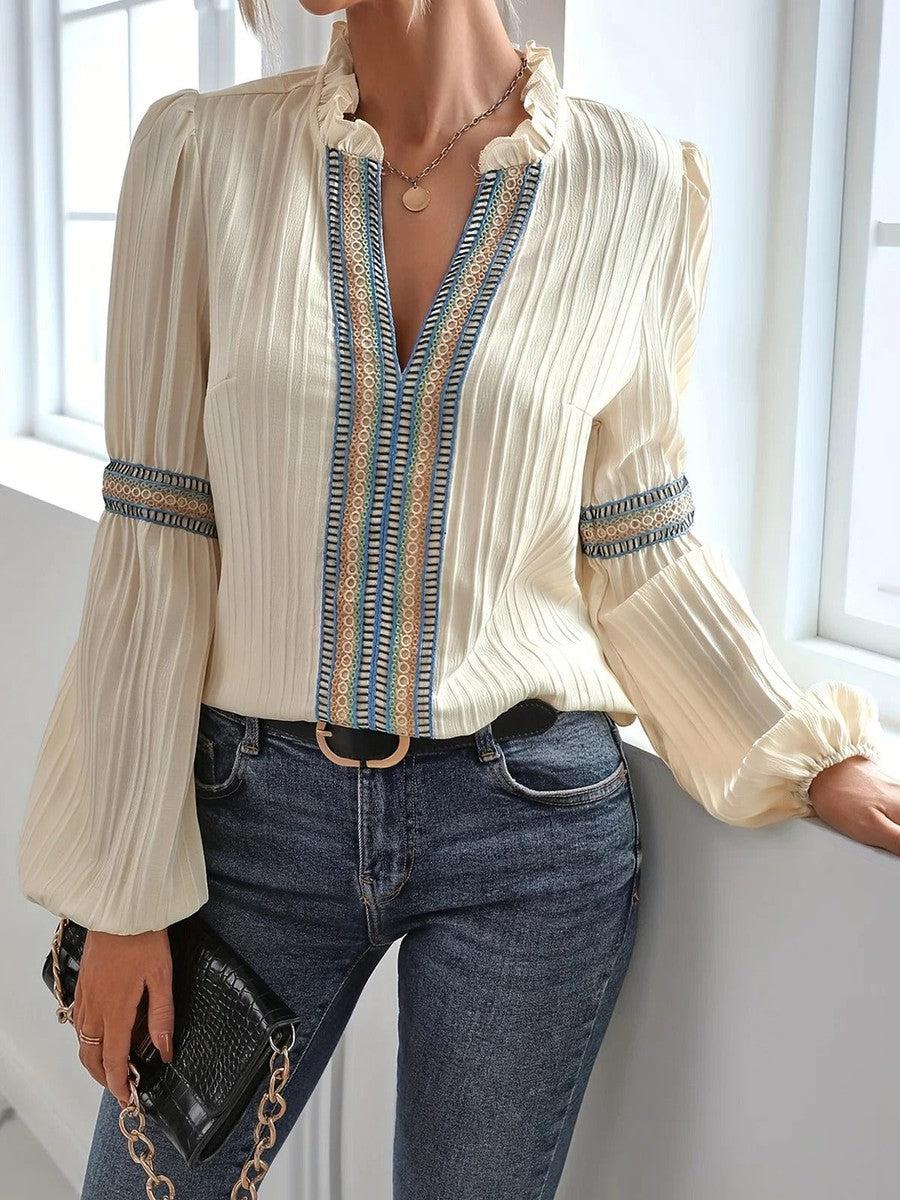 Donna con camicetta bianca elegante a pieghe, dettagli blu e oro, abbinata a jeans aderenti. Look casual chic, moda femminile autunnale.