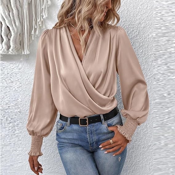 Blusa elegante donna beige, maniche lunghe a sbuffo, scollo a V incrociato, abbinata a jeans casual. Moda femminile, abbigliamento chic.