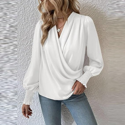 Blusa bianca elegante con maniche lunghe a sbuffo, scollo a V incrociato, indossata con jeans. Moda donna, abbigliamento casual chic.
