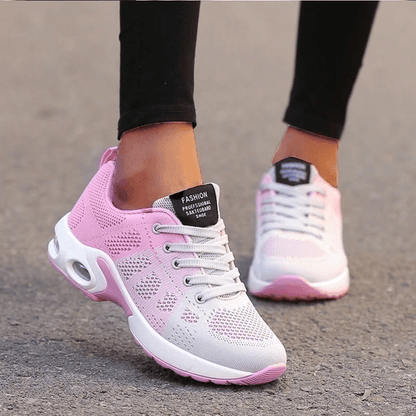 Scarpe da ginnastica rosa e bianche da donna su strada asfaltata, design traspirante, suola ammortizzata, moda casual sportiva.