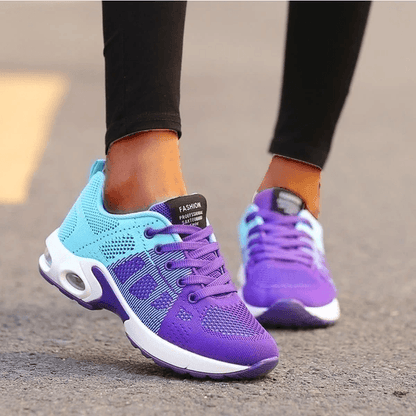 Scarpe da ginnastica viola e azzurre su strada, design sportivo e moderno, suola ammortizzata, ideali per corsa e fitness.