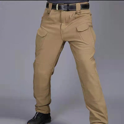 Pantaloni tattici beige da uomo con tasche multiple, cintura nera e scarpe nere. Abbigliamento outdoor resistente e funzionale.
