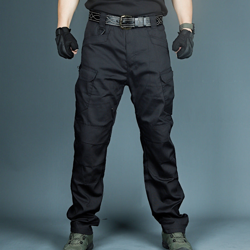 Pantaloni tattici neri con tasche cargo, guanti e scarpe militari. Abbigliamento outdoor resistente, ideale per escursionismo e attività all'aperto.
