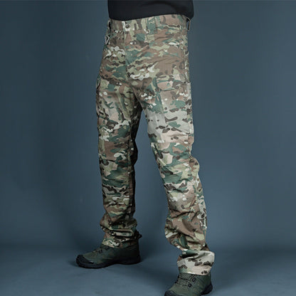 Pantaloni mimetici militari, stile cargo, indossati da una persona in piedi su sfondo grigio. Ideali per outdoor e attività tattiche.